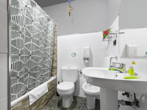 a white bathroom with a toilet and a sink at Hotel San Miguel in Gijón