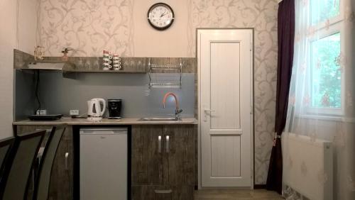 una cucina con un lavandino e un orologio a parete di Эдем a Tbilisi City