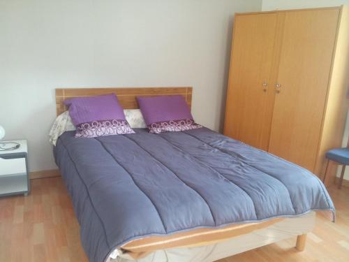 a bedroom with a large bed with purple pillows at pasteur in Cholet