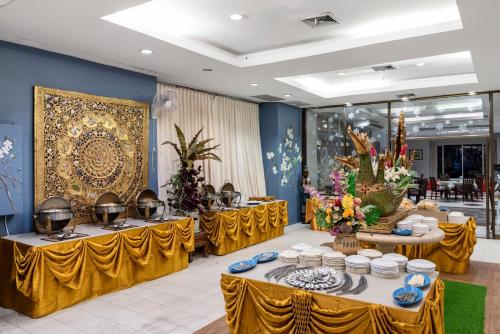 um salão de banquetes com mesas amarelas com pratos e taças em Ayothaya Riverside Hotel em Phra Nakhon Si Ayutthaya