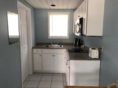 a kitchen with white cabinets and a sink and a window at Ocean Walk Hotel in Old Orchard Beach