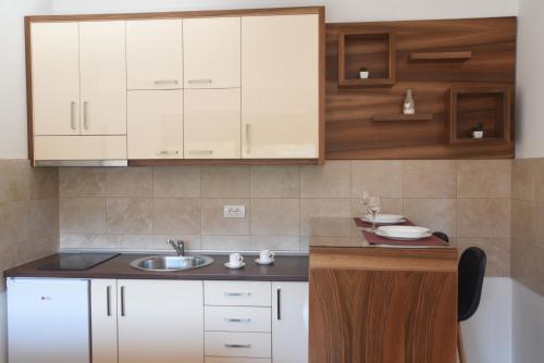 a kitchen with white cabinets and a sink at Apartmani Sunny side sa otvorenim bazenom-besplatan parking in Vrnjačka Banja