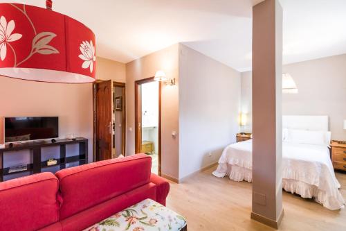 a living room with a red couch and a bed at B&B Concha in Becerril de la Sierra