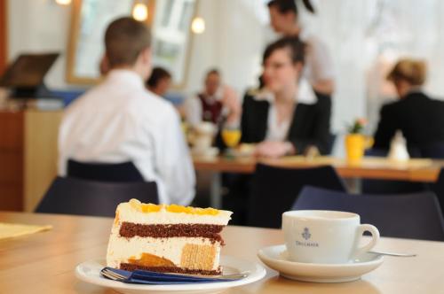 a piece of cake on a table with a cup of coffee at Hotel St Elisabeth in Allensbach