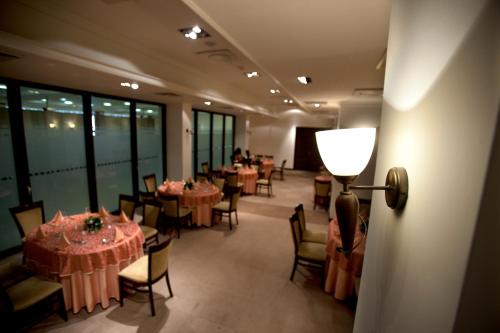 a dining room with tables and chairs and a lamp at Hotel Kragujevac in Kragujevac