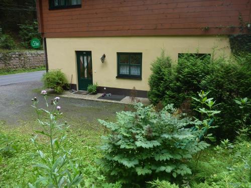 ein Haus mit schwarzer Tür und einigen Pflanzen in der Unterkunft Ferienwohnung UHU neben der Schrammsteinbaude in Bad Schandau