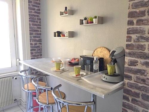 una cucina con bancone, macchina del caffè e sgabelli di L'Appart Bleu - Lumineux F3 Mulhouse Gare/Centre a Mulhouse
