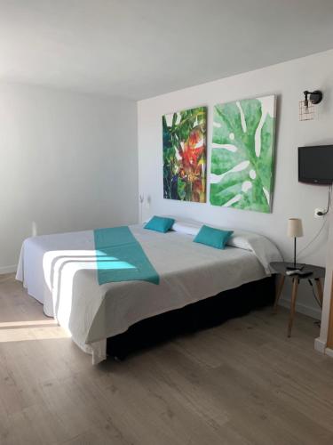 a bedroom with a bed with two paintings on the wall at FORMENTERADREAMING SUITe in La Savina
