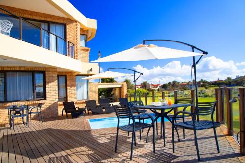a patio with a table and chairs and an umbrella at African Oceans Manor on the Beach in Mossel Bay