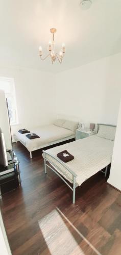 two beds in a living room with wooden floors at Regent Guest House in Burnley