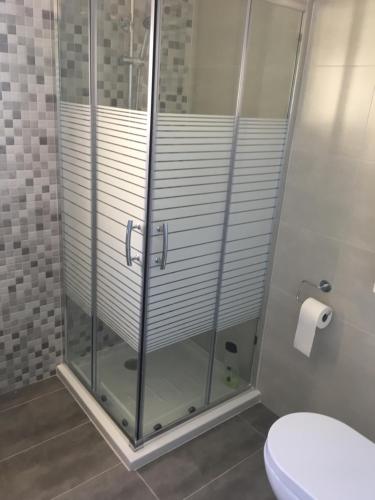 W łazience znajduje się prysznic ze szklanymi drzwiami oraz toaleta. w obiekcie Piso de lujo a estrenar w Kadyksie