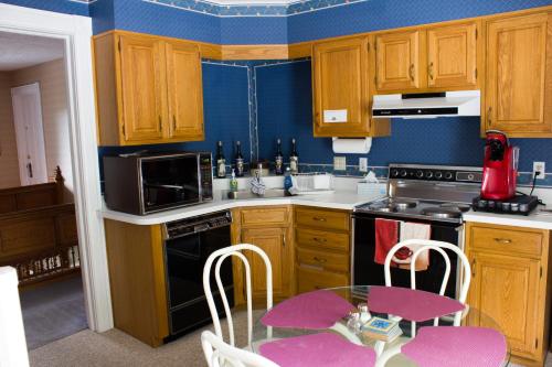 a kitchen with wooden cabinets and a table with pink chairs at Hudson Manor Bed & Breakfast in Watkins Glen
