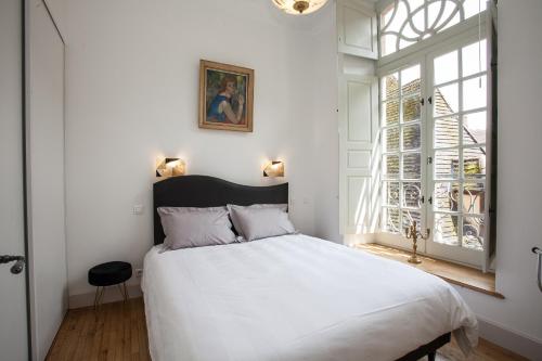 a bedroom with a large white bed and a window at LE GENIS in Sarlat-la-Canéda