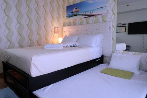 um quarto com 2 camas e lençóis brancos em Stay and Fly at Amani Grand Resort Residences em Mactan