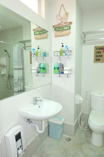 a white bathroom with a sink and a toilet at Stay and Fly at Amani Grand Resort Residences in Mactan