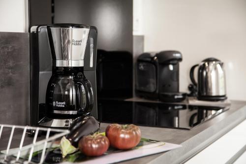 deux pommes assises sur un comptoir à côté d'une cafetière dans l'établissement LE GENIS, à Sarlat-la-Canéda