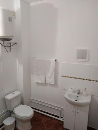 a white bathroom with a toilet and a sink at Residêncial Carlos Carvalho in Praia