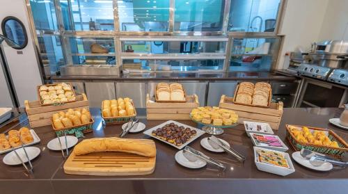 a table with different types of bread and pastries at Comfort Suítes Vitória in Vitória