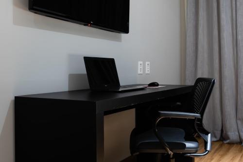 a black desk with a laptop and a chair at Comfort Suítes Vitória in Vitória