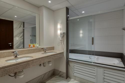 a bathroom with two sinks and a glass shower at Comfort Suítes Vitória in Vitória