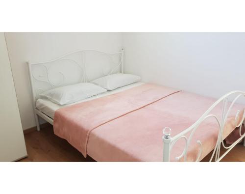 a bedroom with a white bed with a pink blanket at Studio apartman, 2+1 in Brodarica