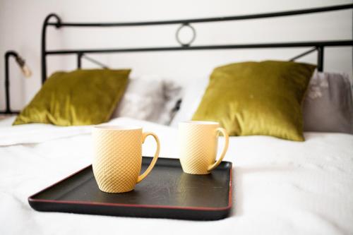 two coffee mugs sitting on a tray on a bed at Apartments Castello Risano in Risan