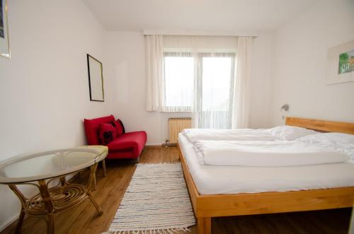 ツェル・アム・ゼーにあるLandhaus Pibergerのベッドルーム1室(ベッド1台、テーブル、赤い椅子付)