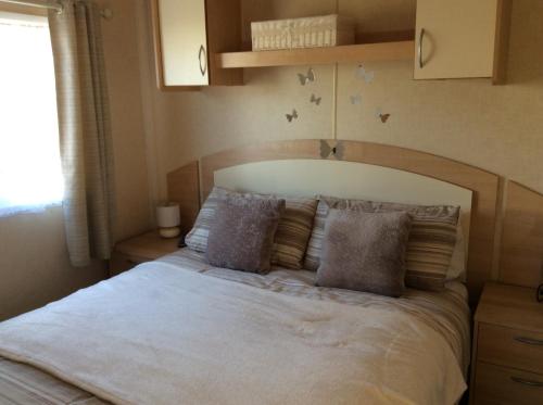 una camera da letto con un grande letto bianco con cuscini di 74, Orchard Park a Paignton