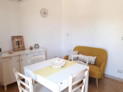 a dining room with a white table and a yellow chair at Sun & Sea, holidays home in Fontane Bianche