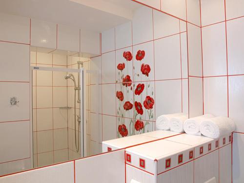 a bathroom with a shower and red flowers on the wall at Zdrowotel Łeba in Łeba