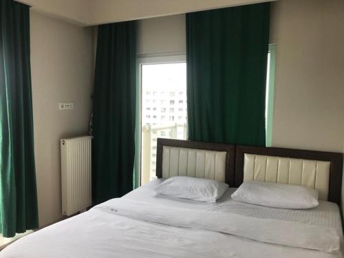 een slaapkamer met een bed met groene gordijnen en een raam bij Medıkule (7) 1+1 in Istanbul