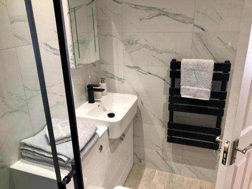 W białej łazience znajduje się umywalka i lustro. w obiekcie Apartment 4, 1 Laura Place w Aberystwyth