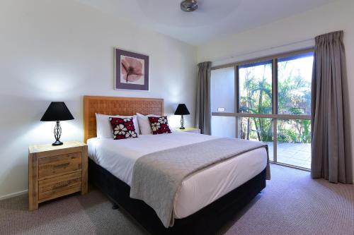 a bedroom with a large bed and a large window at Cooinda Gardens in Hamilton Island