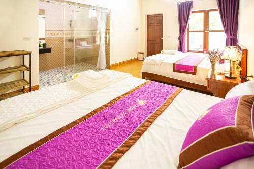a bedroom with two beds with purple and white sheets at Ruby Homestay in Ninh Binh