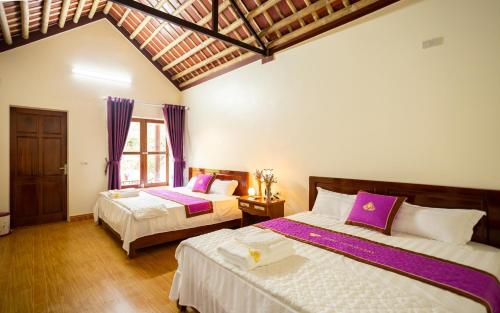 a bedroom with two beds with purple and white sheets at Ruby Homestay in Ninh Binh