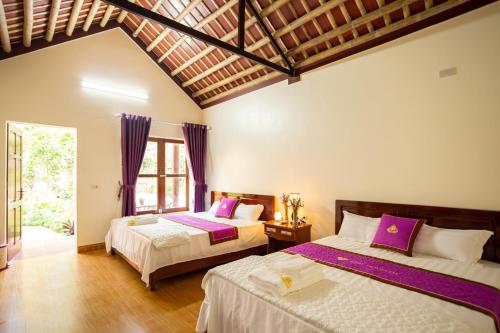 a bedroom with two beds with purple and white sheets at Ruby Homestay in Ninh Binh