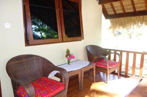une chambre avec deux chaises, une table et un balcon dans l'établissement Rumah Sunyi, à Gili Trawangan