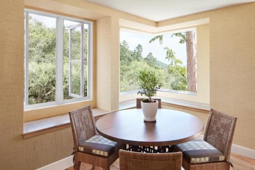 a dining room with a table and two windows at Auberge du Soleil, An Auberge Resort in Rutherford
