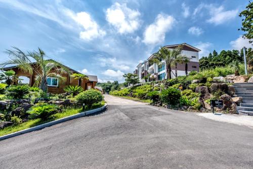 an empty street with houses and palm trees at Jeju I've Hotel & Resort in Seogwipo