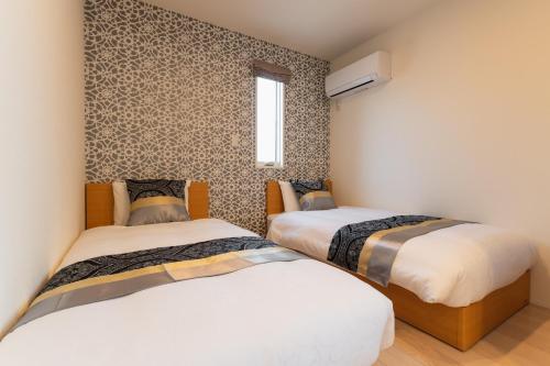 a bedroom with two beds and a window at Ambicia Sasebo in Sasebo