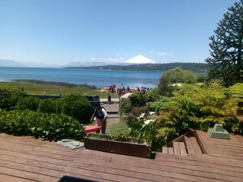 un hombre parado en un jardín con vistas al agua en Volcano & Lake Family Hostel, en Villarrica