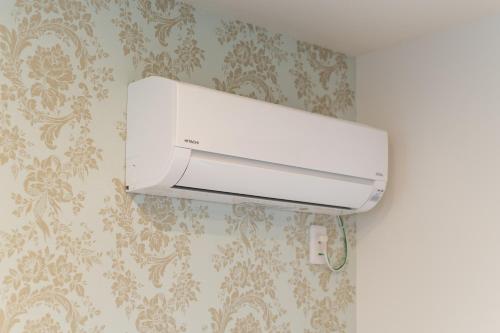 a white printer hanging on a wall with wallpaper at Ambicia Sasebo in Sasebo