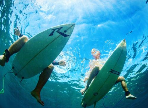 een groep mensen die met surfplanken in het water zwemmen bij Balangan Inn Surf Homestay in Jimbaran