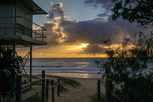 a building on the beach with a sunset at San Marino by the Sea Apartments in Marcoola
