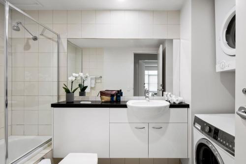 a white bathroom with a sink and a washing machine at Quest Narre Warren in Narre Warren