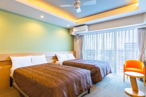a hotel room with two beds and a window at Yenns Marina Inn Mercy in Ginowan