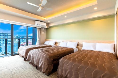 2 łóżka w pokoju hotelowym z oknem w obiekcie Yenns Marina Inn Mercy w mieście Ginowan
