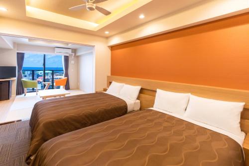 a bedroom with two beds and a large window at Yenns Marina Inn Mercy in Ginowan