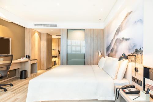 Habitación de hotel con cama grande y escritorio. en Atour Jiaozhou Qingdao Hotel, en Qingdao