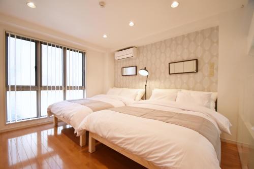 three beds in a room with white walls and windows at TERRACE HOUSE Shibuya Maruyamacho in Tokyo